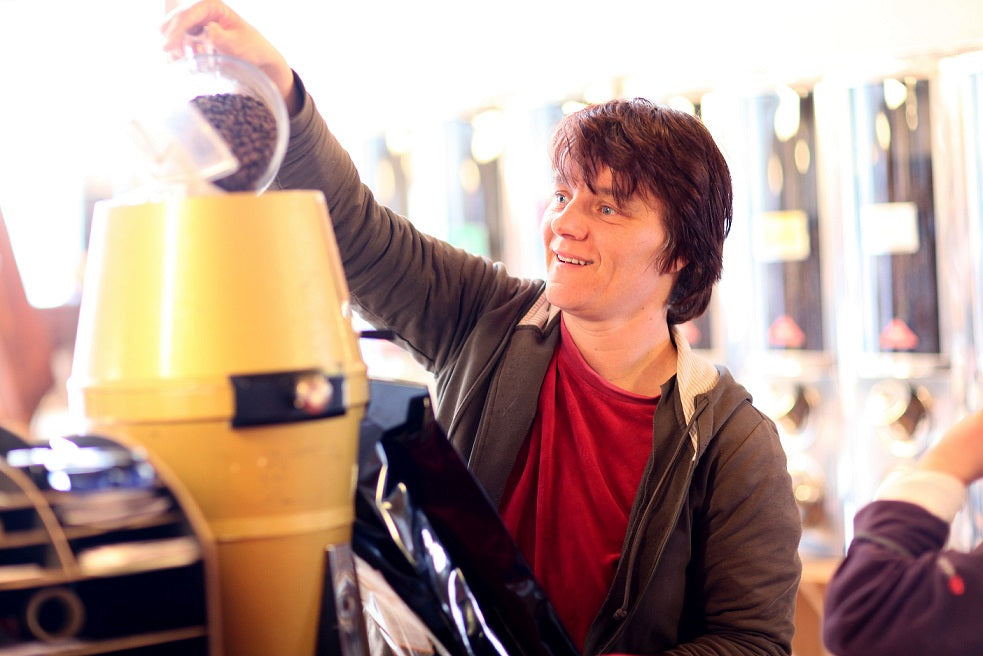 Ein Mitarbeiter der Kaffeerösterei schüttet Kaffeebohnen in eine Röstmaschine