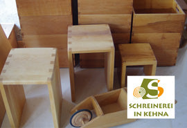 Höcker, Holzkisten und weitere Werkstücke aus Holz mit dem Logo der Schreinerei